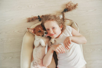Little girl was embracing a puppy on wood background.