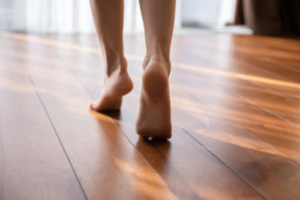Woman walking barefoot on toes at warm laminate floor