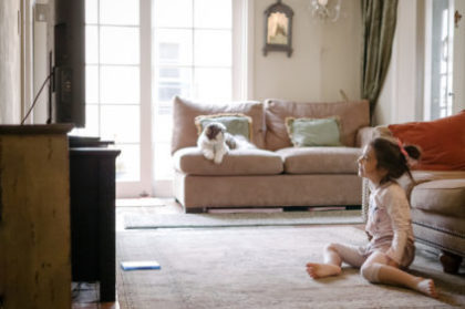 Pretty little girl watching a DVD on TV at home