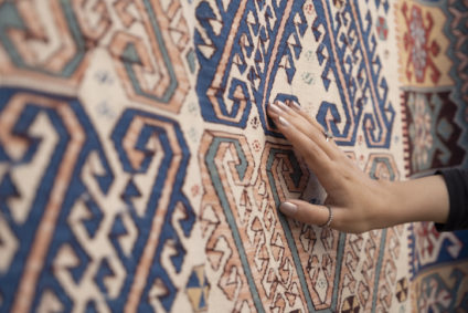 Young woman touching the traditional turkish carpet.