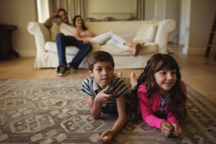 Parents and kids watching television in living room at home