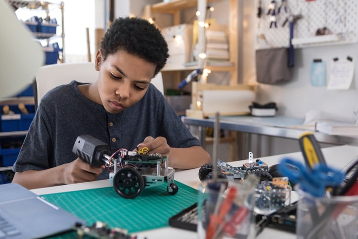 boy solders wires to build robot