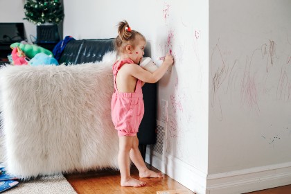 baby girl drawing with marker on wall