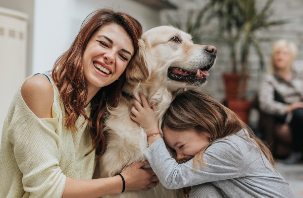 Happy mother and daughter embracing their golden retriever at home